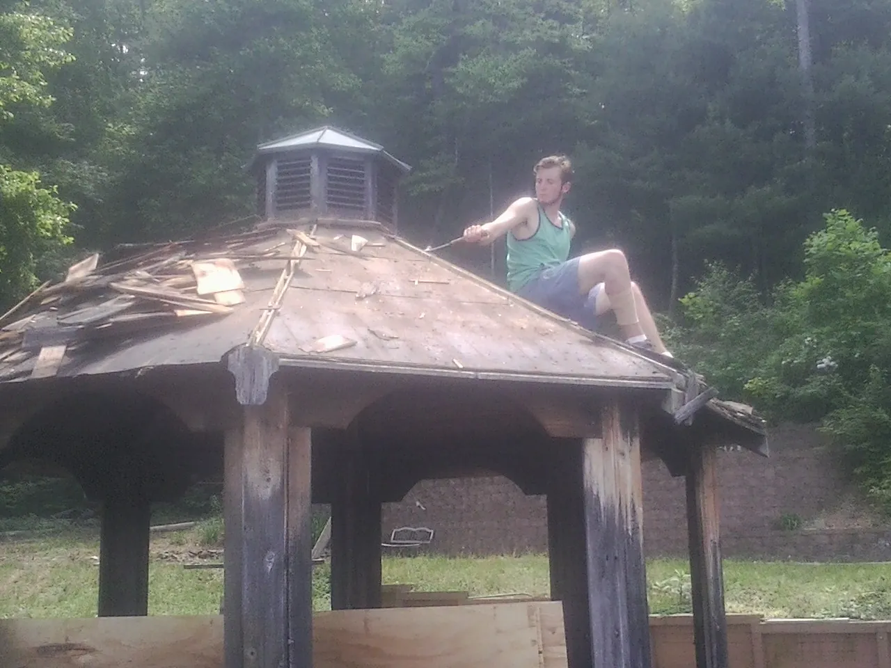 Tearing the old roof off a wooden gazebo before new shakes in Justin