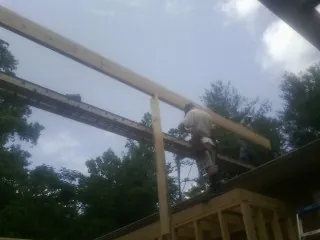 Carpenter setting a ridge beam over a new addition frame — Ice Dam Removal by Roofing Brothers in Justin