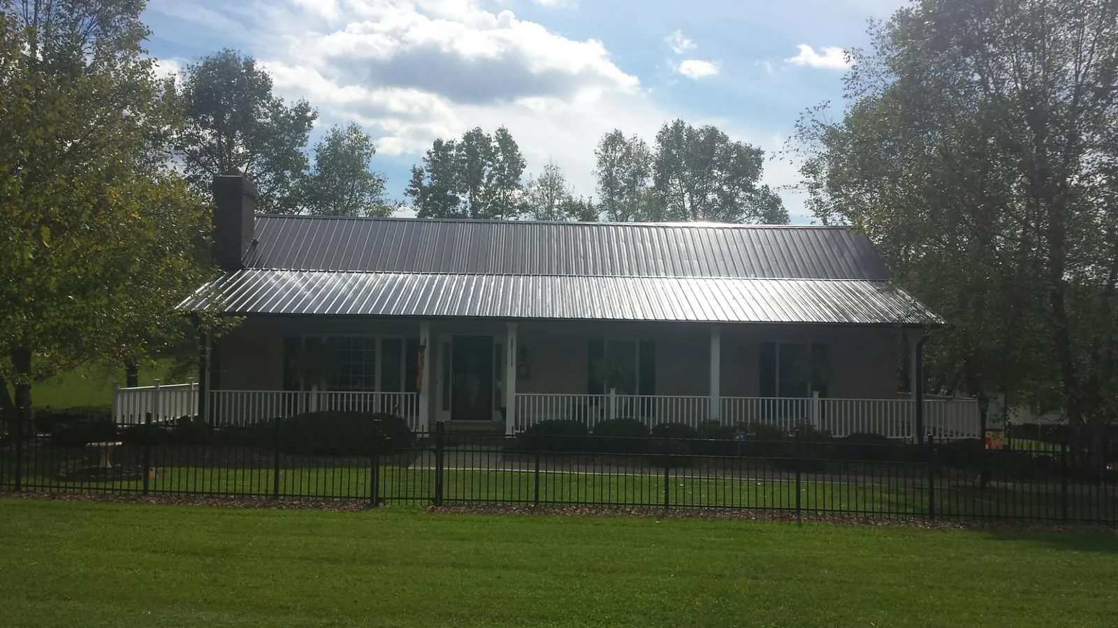 Gray metal roof on a brick ranch with a full width front porch — Gutter Guard Installation work by our crew in Justin