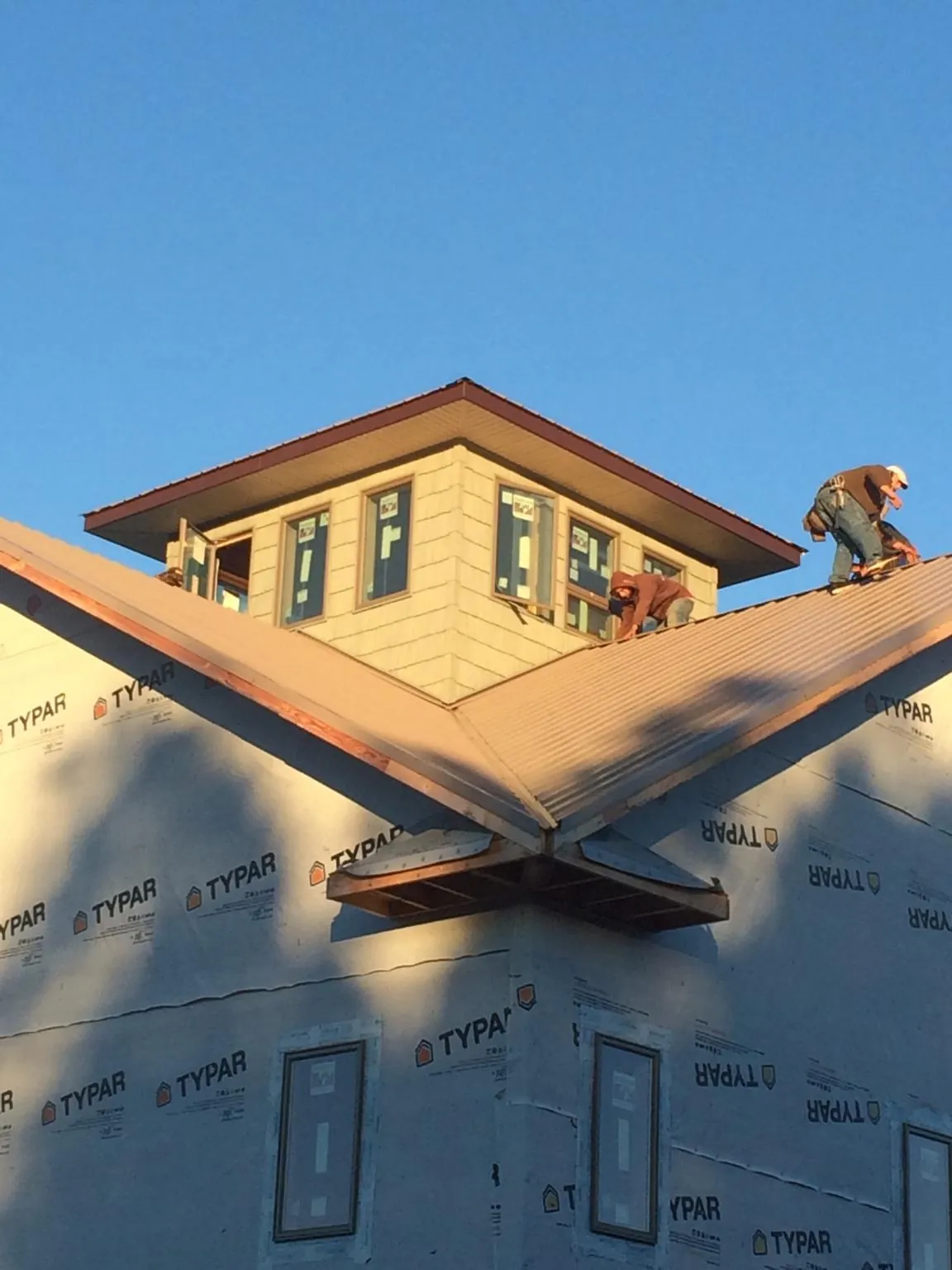 Roofers working around a rooftop cupola on a new metal roof at sunset — Roof Waterproofing in Justin by Roofing Brothers